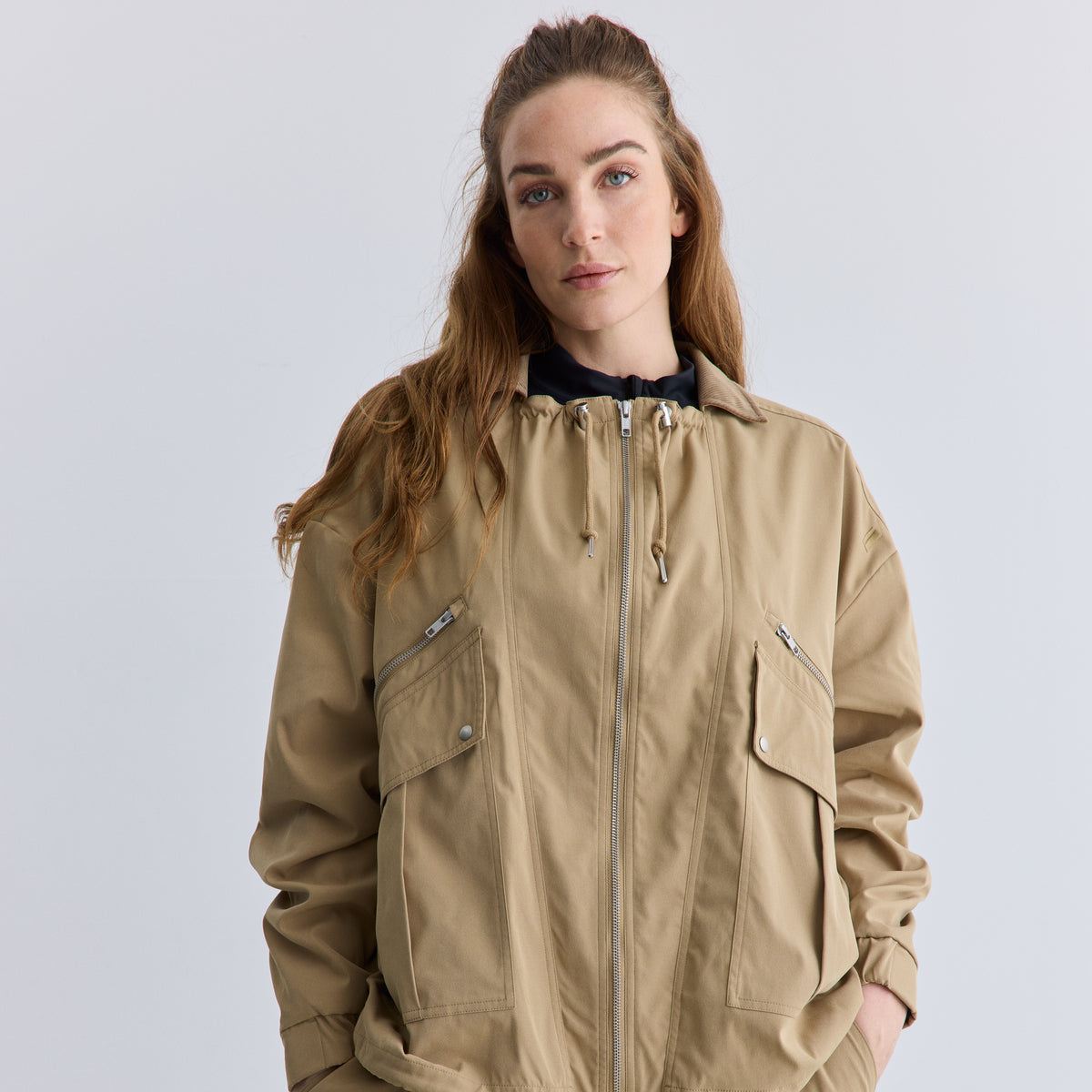 Woman wearing a beige jacket on a plain background