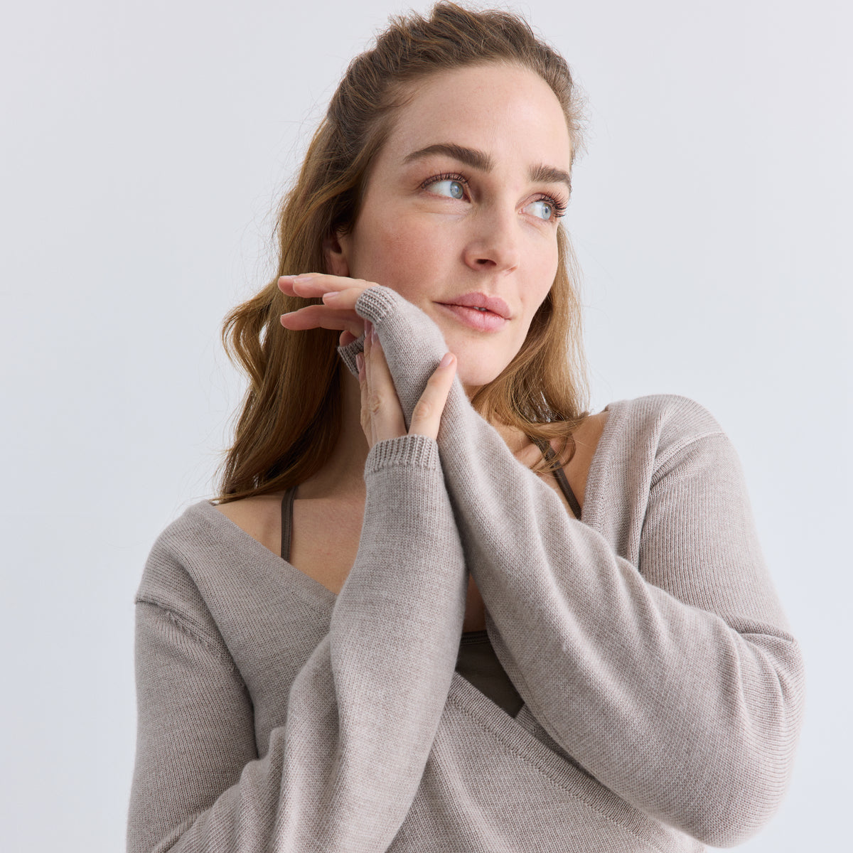 Woman wearing a gray sweater against a light background