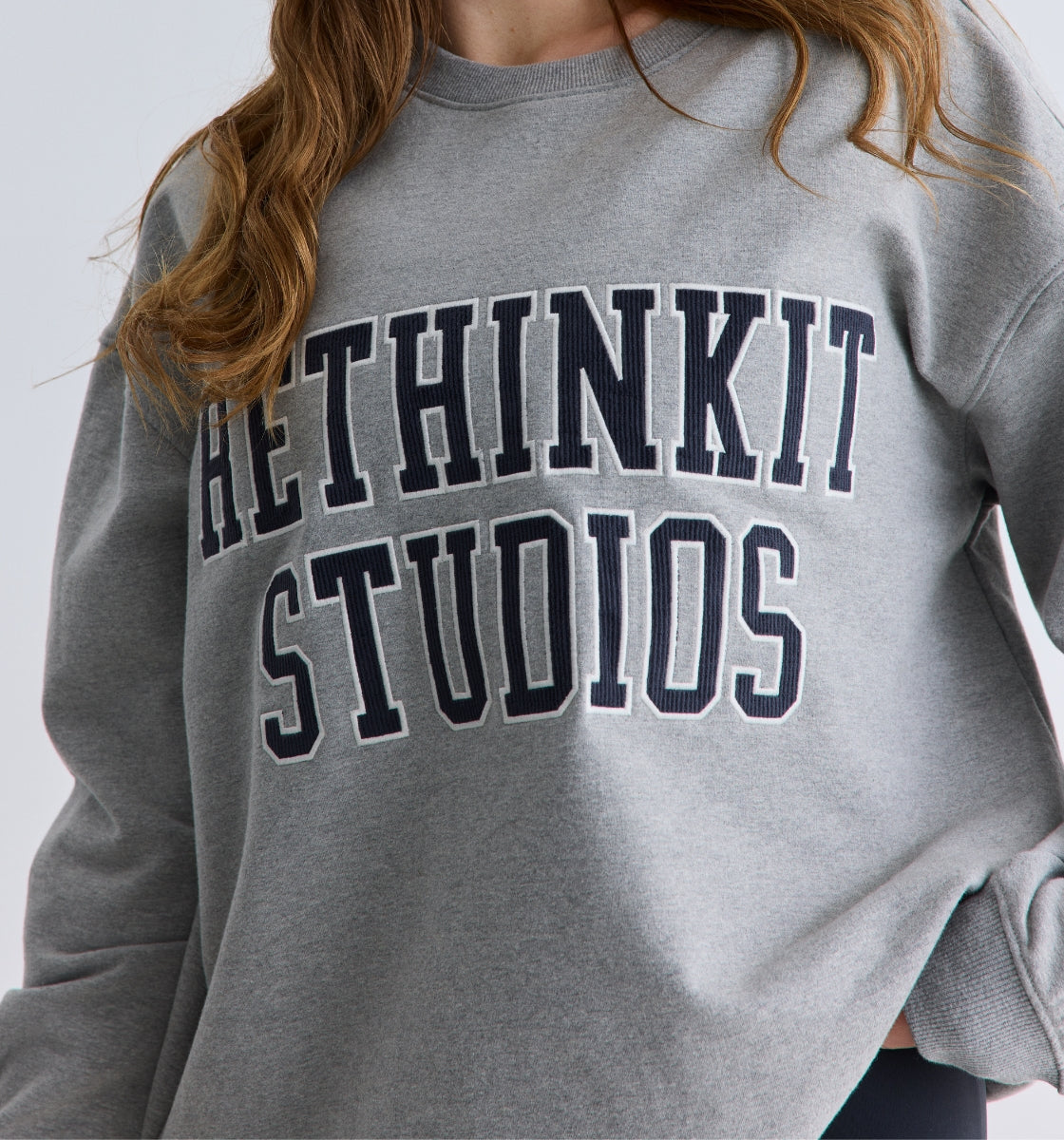 Gray sweatshirt with 'RETHINKIT STUDIOS' text worn by a person